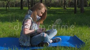 一个<strong>女孩</strong>坐在公园里拿着笔记本电脑。 一个十几岁的<strong>女孩</strong>坐在地毯上呼吸新鲜空气。 阳光明媚的一天，一个带着笔记本电脑的<strong>女孩</strong>